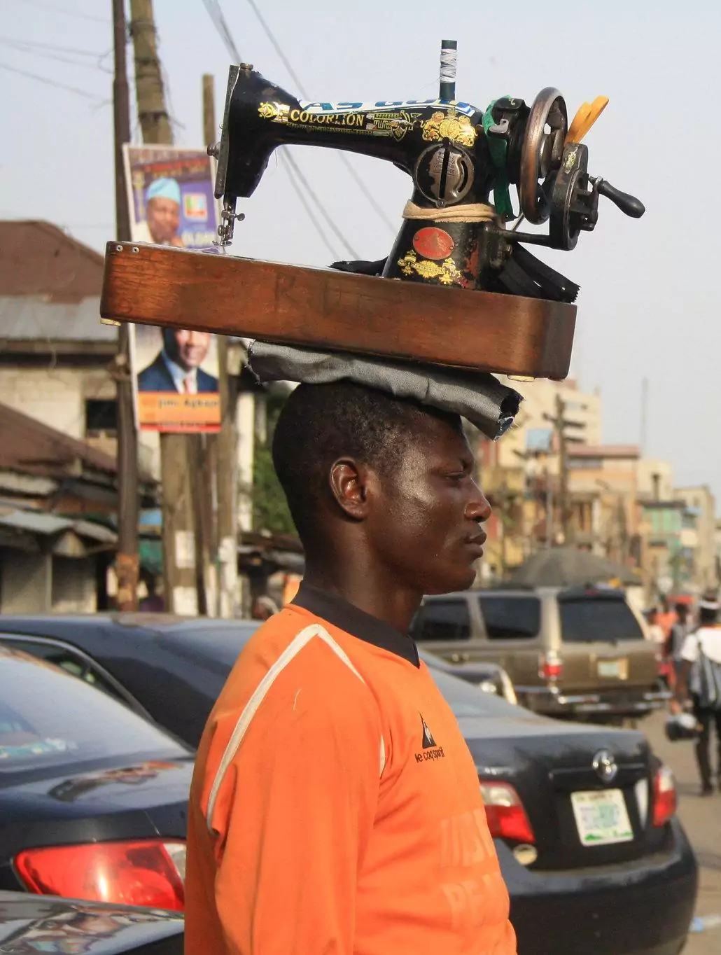 Mobile tailor carrying sewing machine on his head