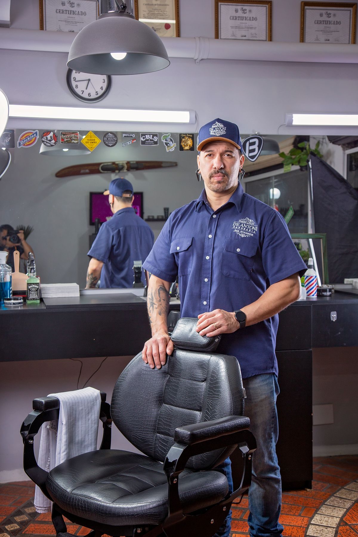 Barber standing by his chair in the shop he runs