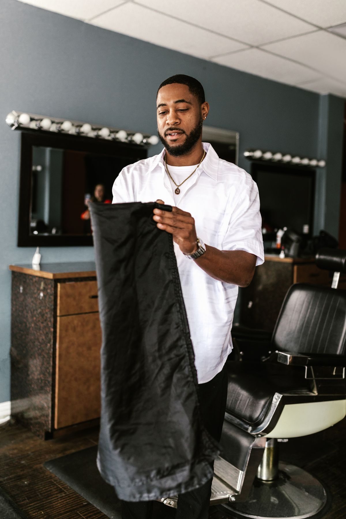 Barber finishing a cut with the cape still on his customer