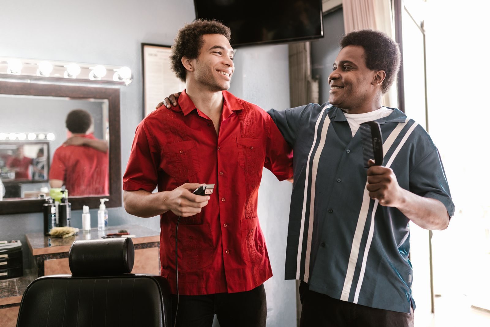 Two barbers checking their phones between clients